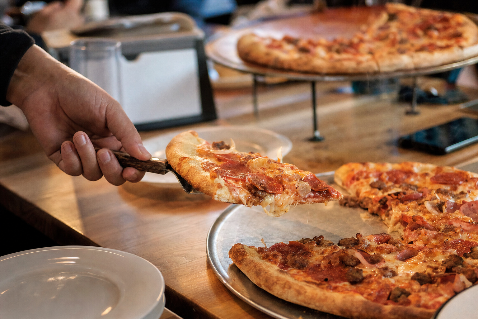 Garçom servindo uma fatia de pizza quente do rodízio numa pizzaria de família