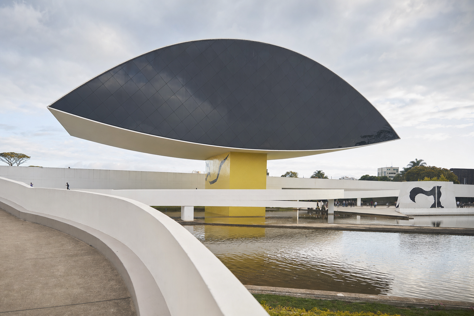 Museu moderno com estrutura suspensa em forma de olho sobre espelho d'água, evocando o Museu do Olho em Curitiba