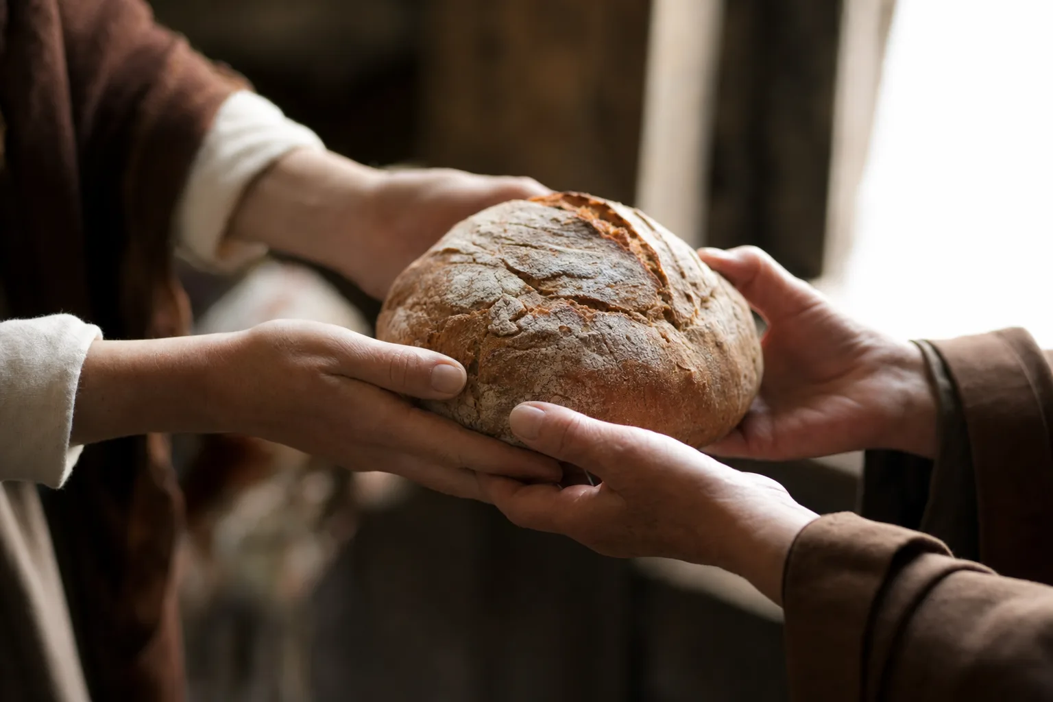 Mãos oferecendo um pão à luz quente, evocando generosidade e o ato de dar