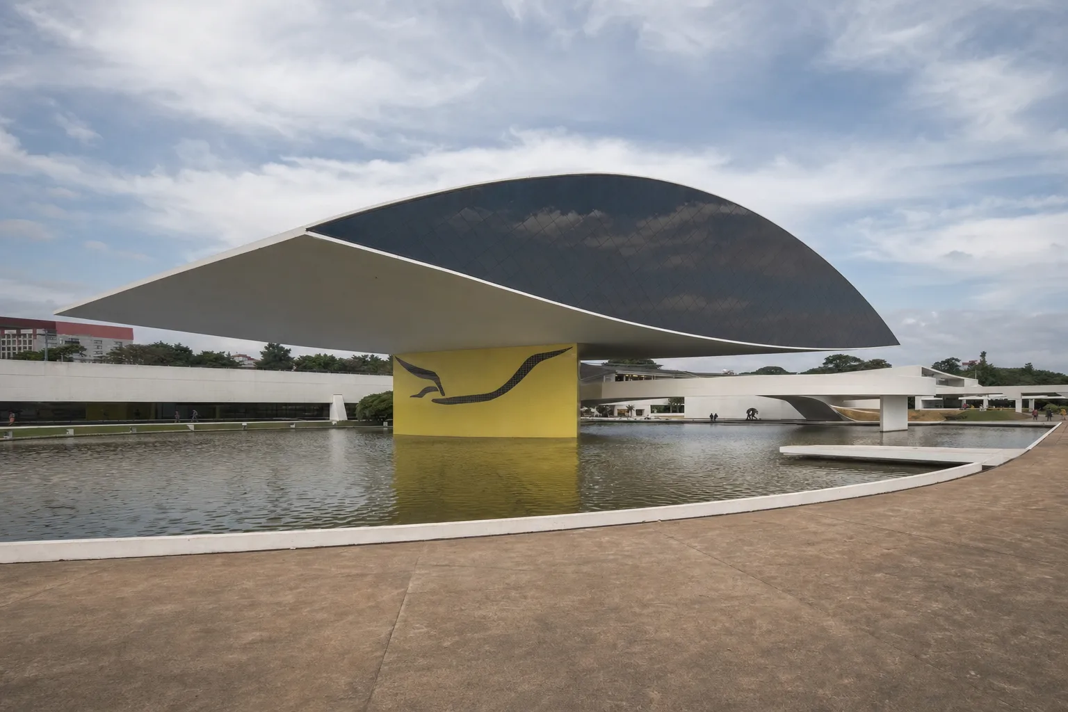 Museu moderno com estrutura suspensa em forma de olho sobre espelho d'água, evocando o Museu do Olho em Curitiba